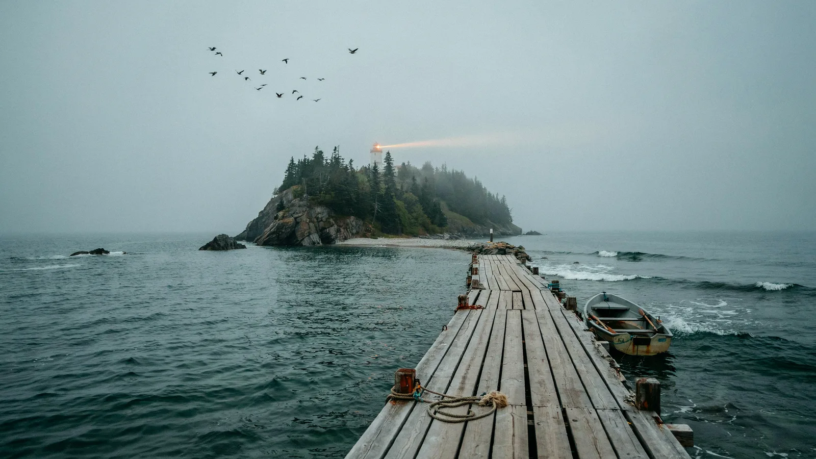 A wooden dock leading to a fog-covered lighthouse island with a rowboat, titled Best Series Set on Islands.